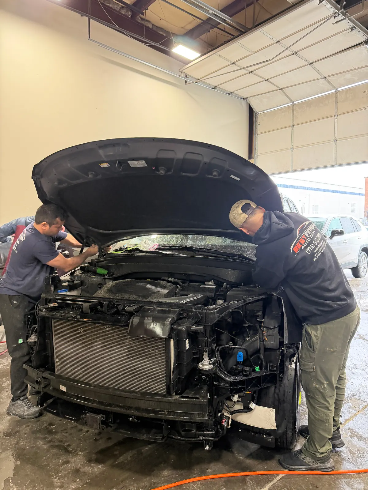 Best Finish technicians fitting a replacement hood on a customer vehicle